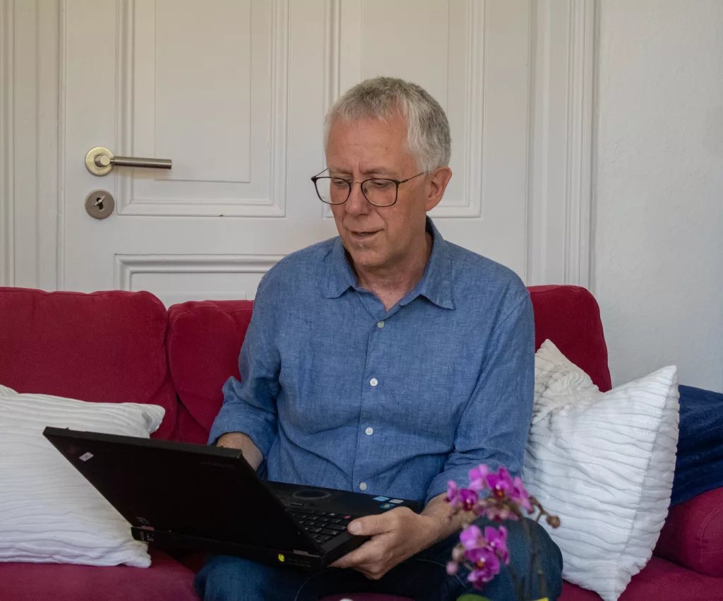 Psychologischer Ernährungsberater Edgar Schröer hält ein Laptop zur Onlineberatung vor sich.